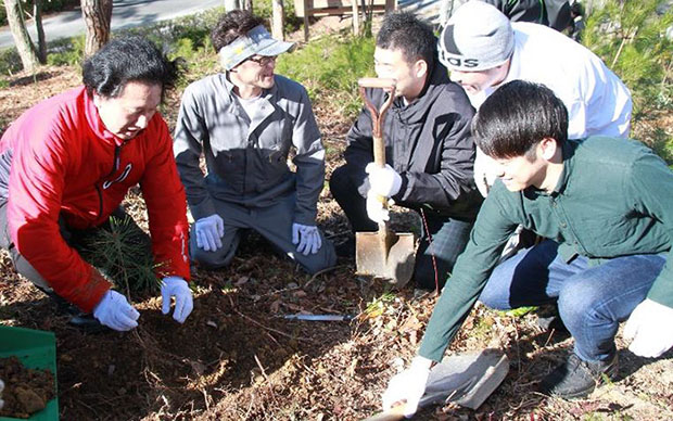 社員と植樹をする社長の津村（写真左）